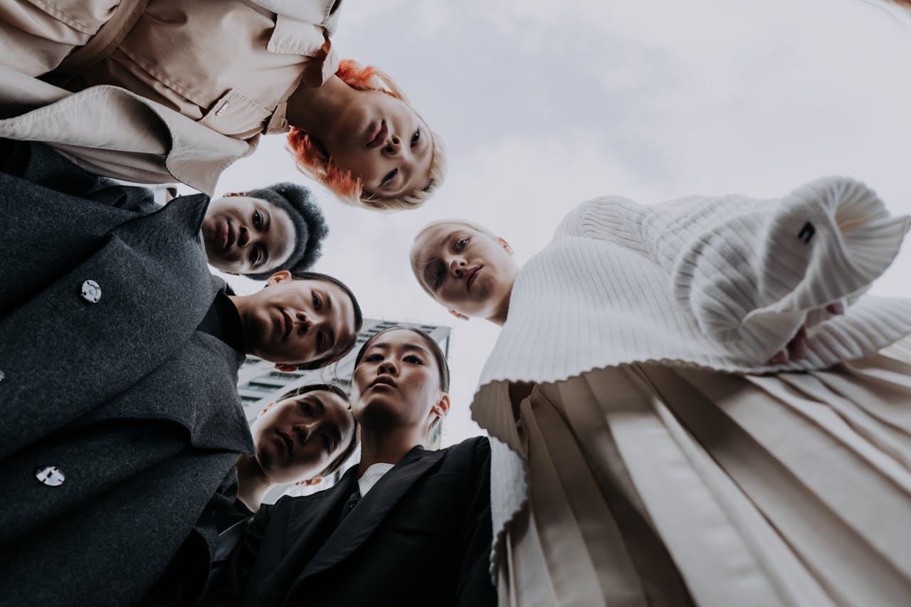 Low angle view of a diverse group of women in stylish clothing, standing together outdoors.